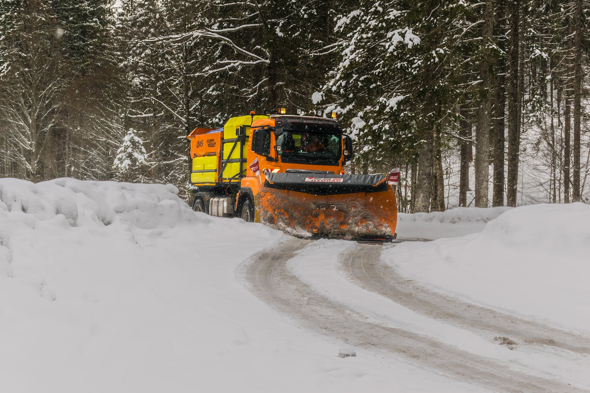 yellow orange and black truck plowing snow