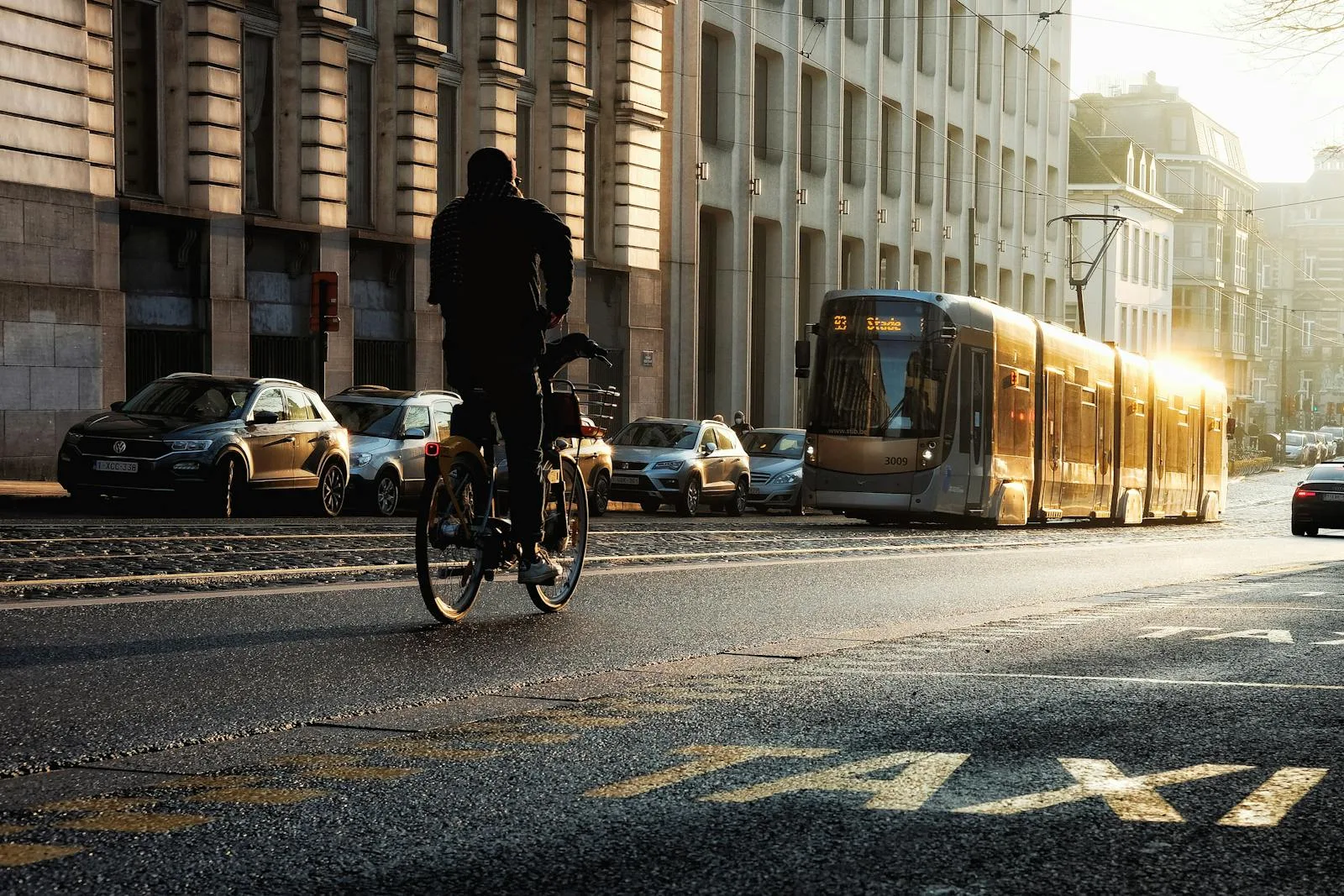A cyclist and tram in motion on a sunny street in Brussels, reflecting urban life.