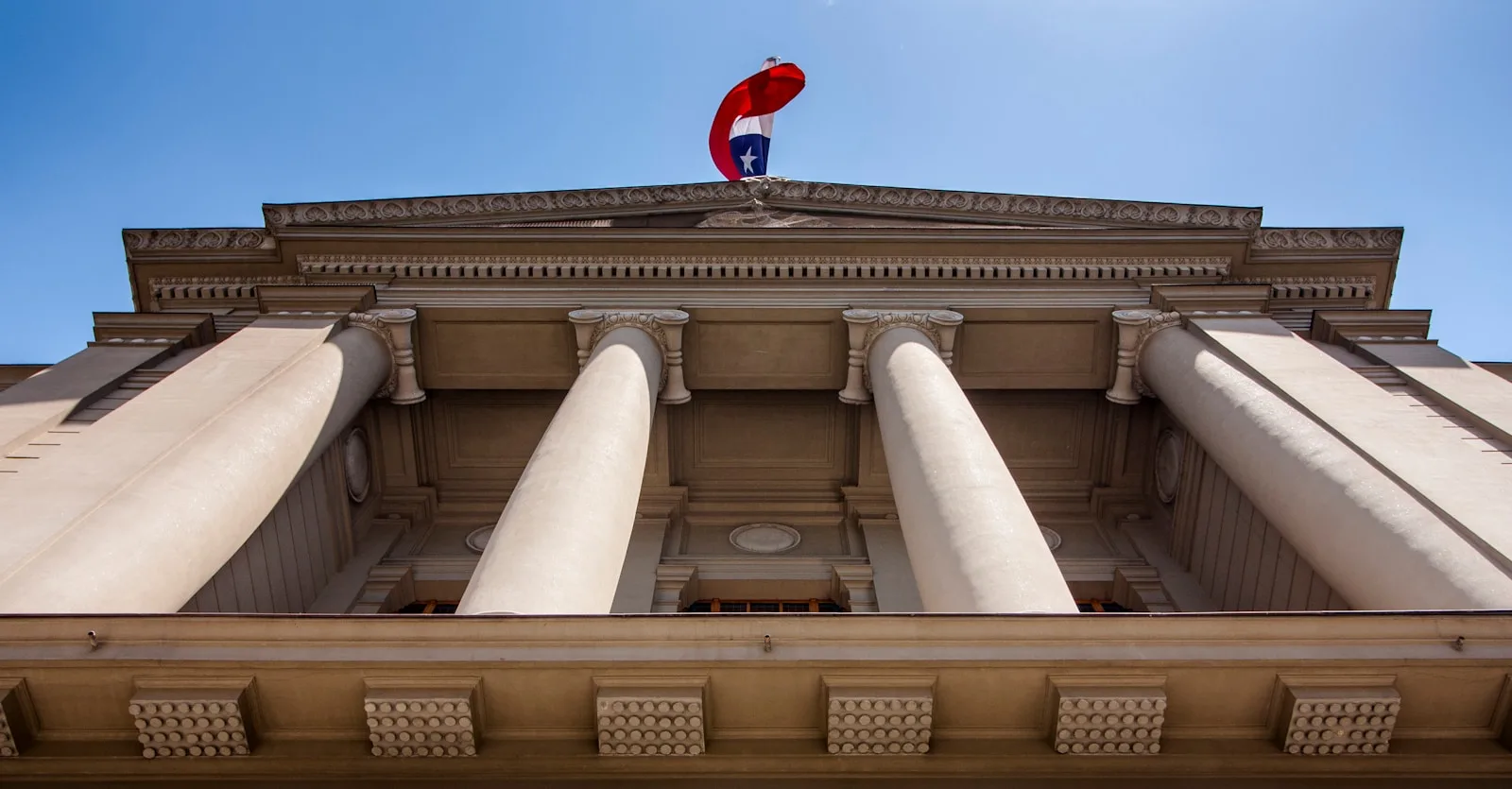 a tall building with columns and a flag on top