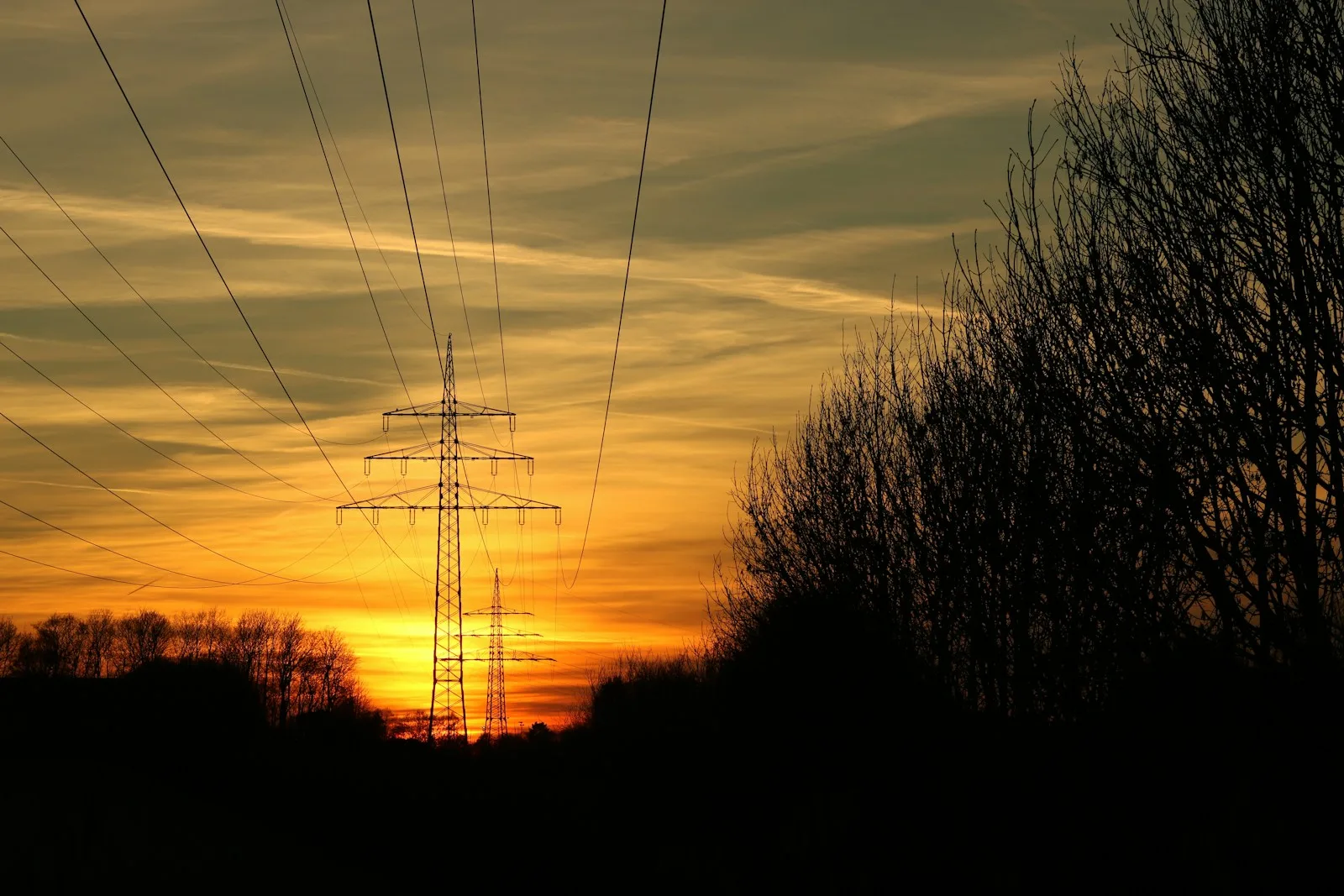 the sun is setting behind the power lines