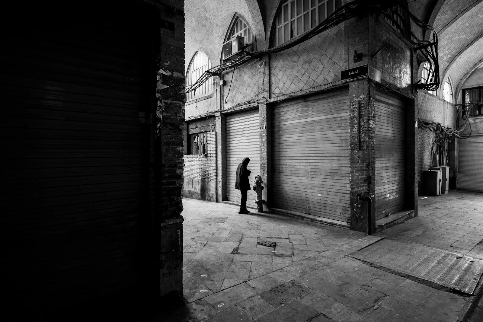 grayscale photo of man walking on sidewalk