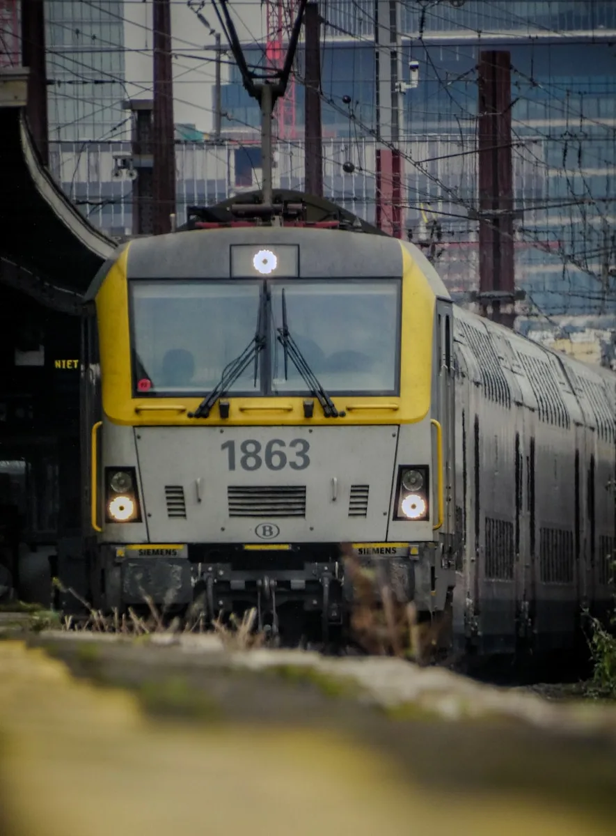 A yellow and gray train traveling down train tracks