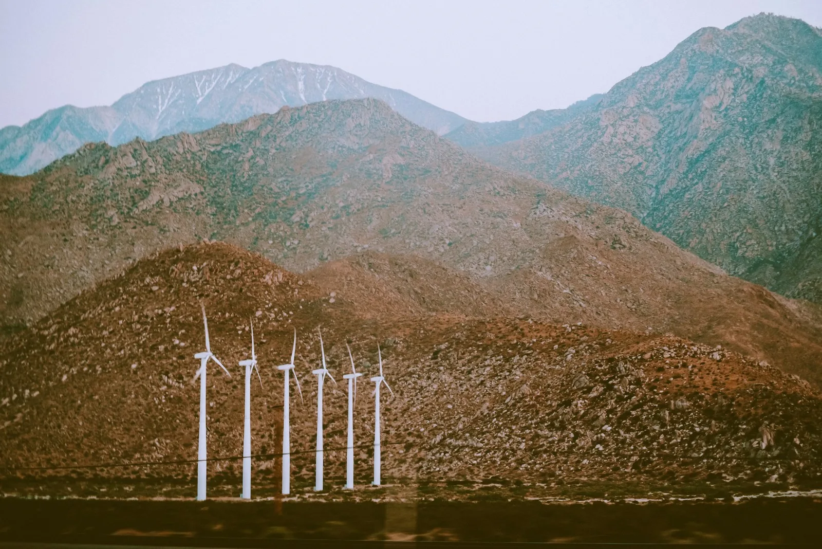 white metal fence near body of water and mountain during daytime