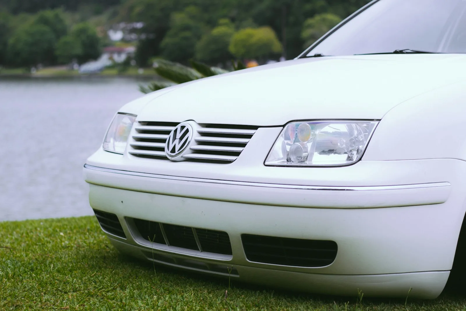 a white car parked on top of a lush green field