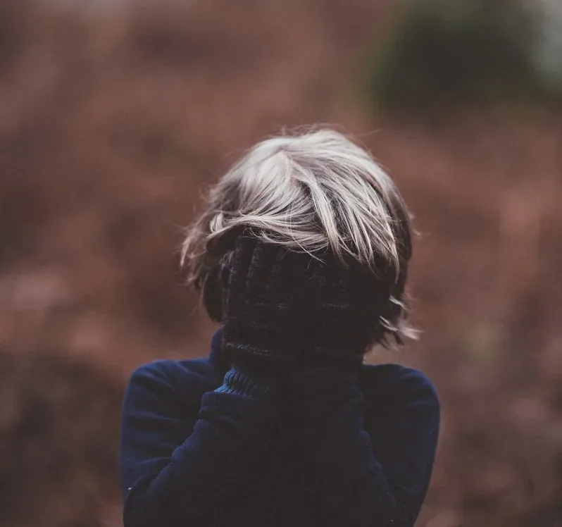 selective photo focus of person covering face