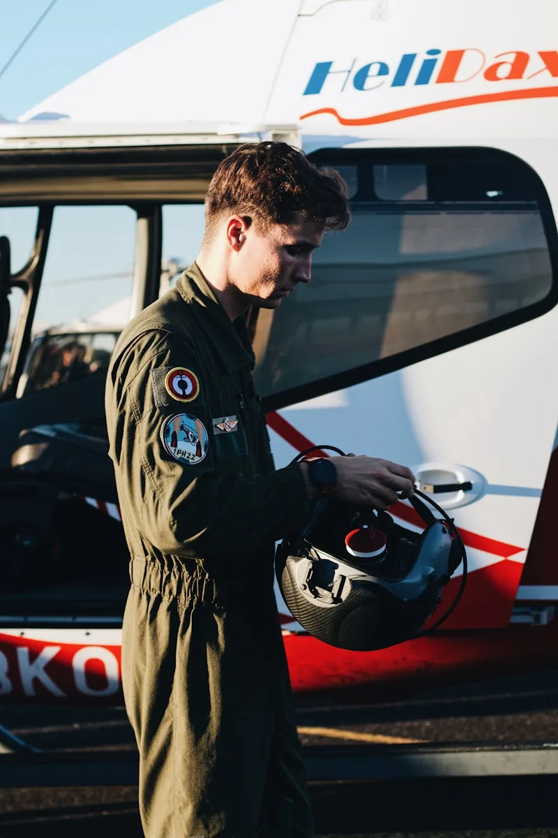 a man in a pilot's uniform standing in front of a helicopter