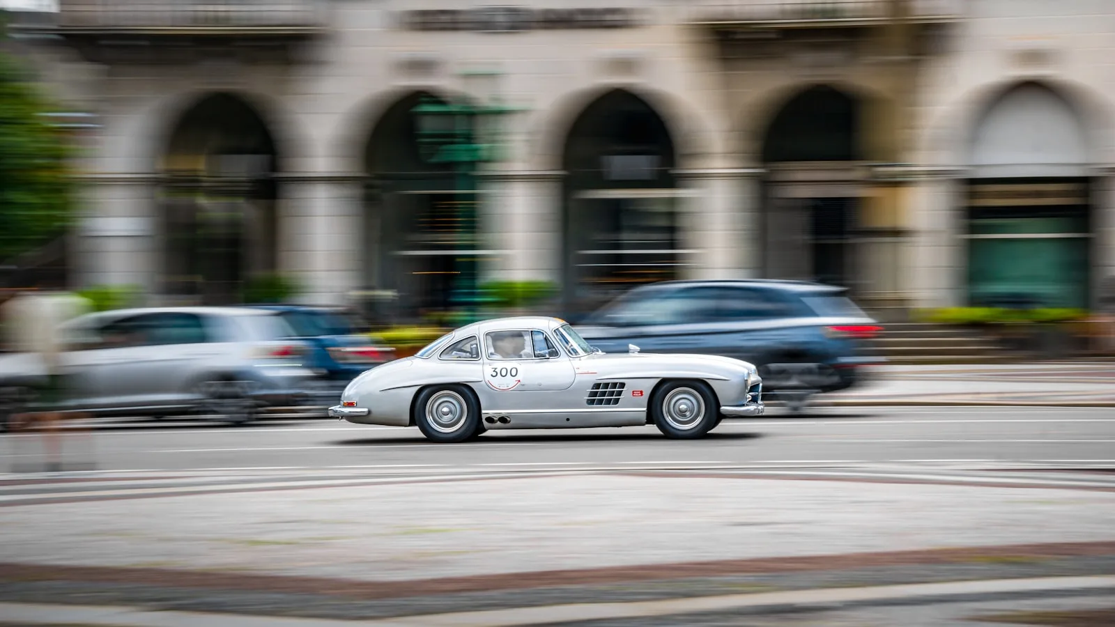 A white car driving down a street next to tall buildings