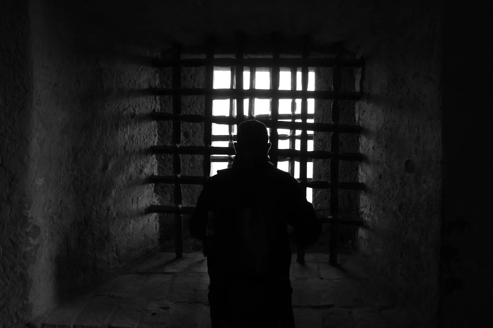 silhouette of man standing in front of window prison