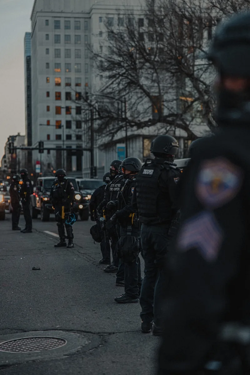 people in black uniform walking on street during daytime