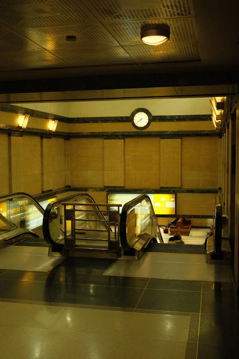 an escalator in a building with a clock on the wall