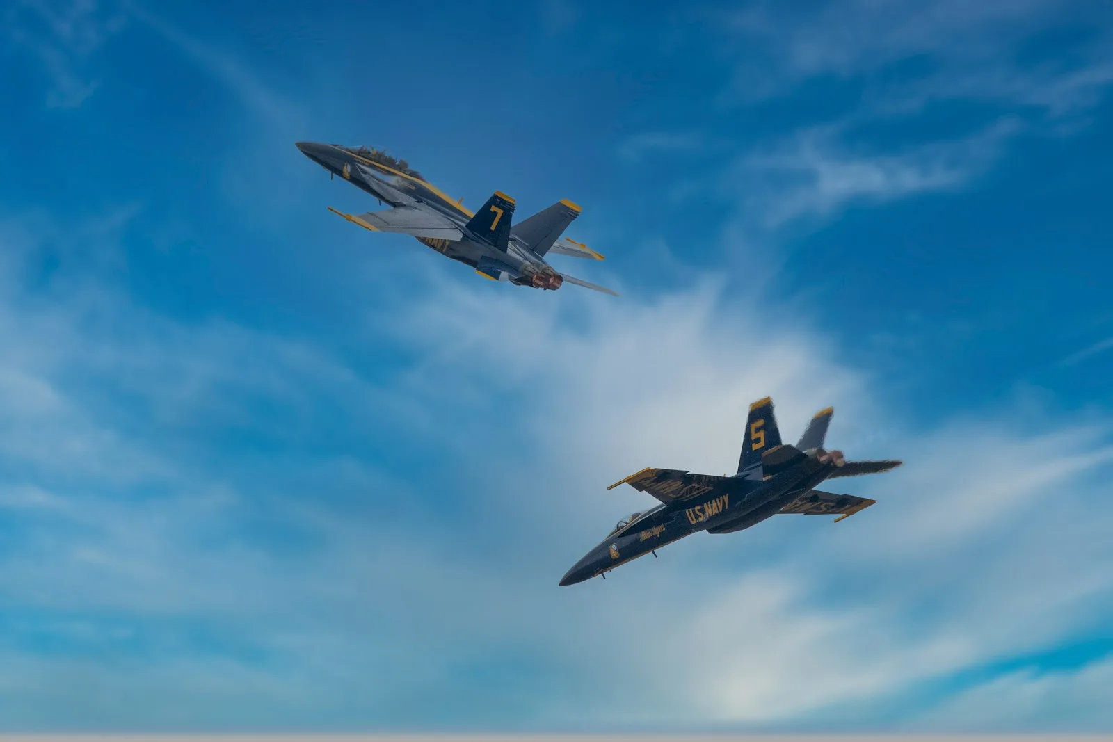 two fighter jets flying through a blue cloudy sky