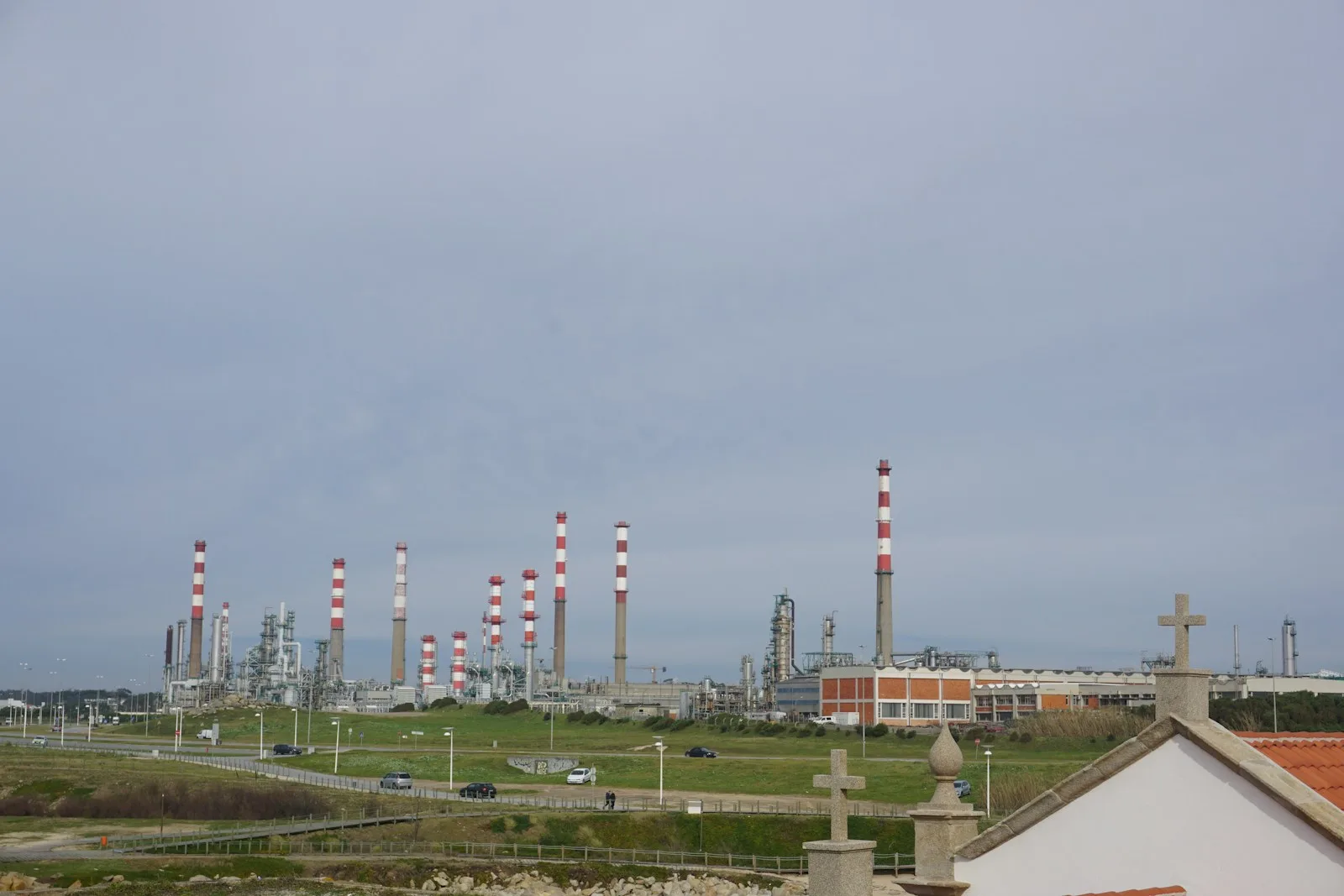 Oil refinery chimneys stand under a cloudy sky.