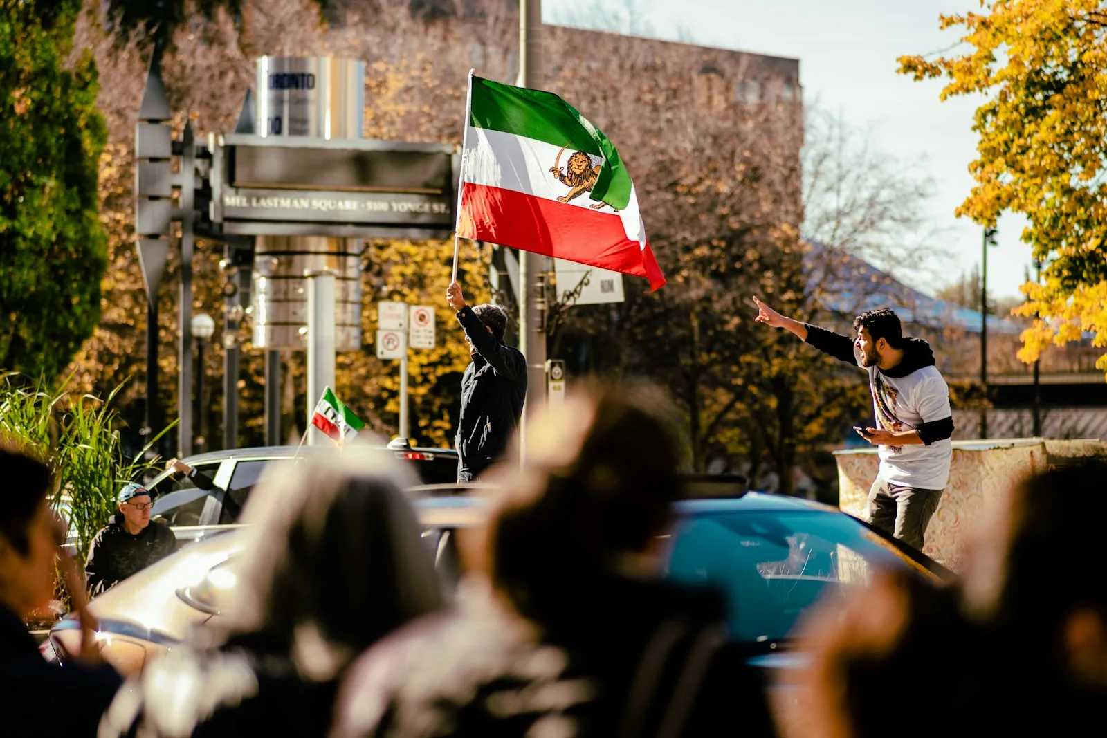 a group of people on a street with a person holding a flag