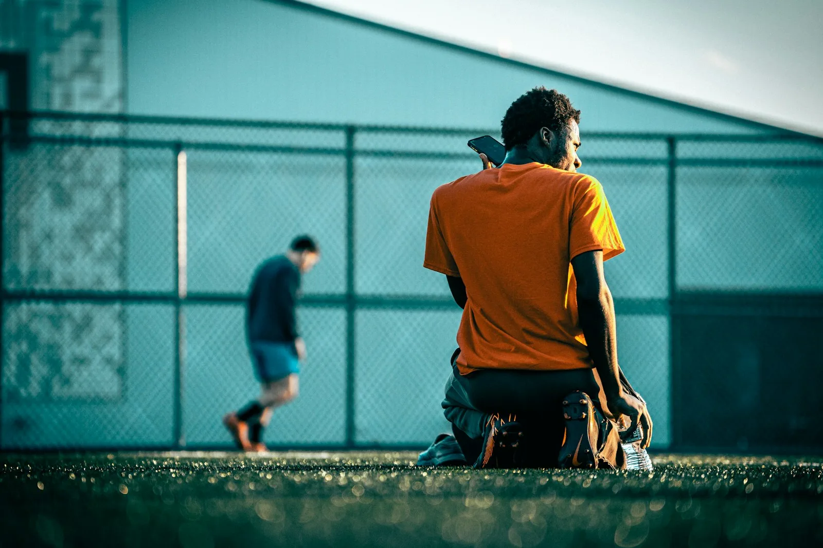 a man sitting on a bench in front of a fence