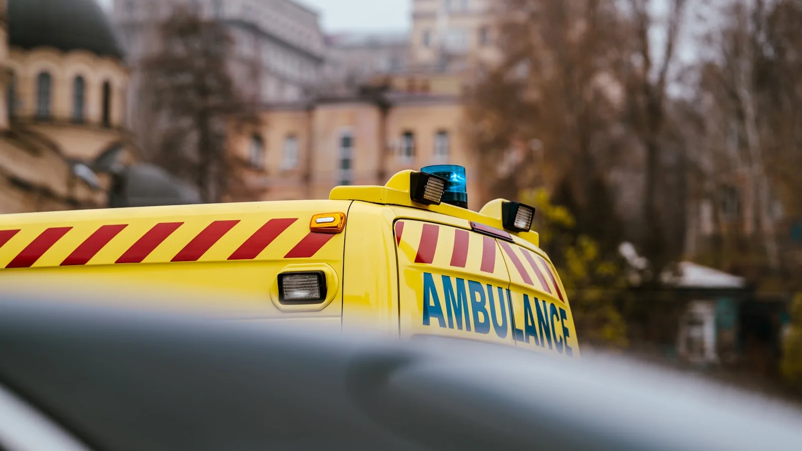 a yellow ambulance is parked in front of a building