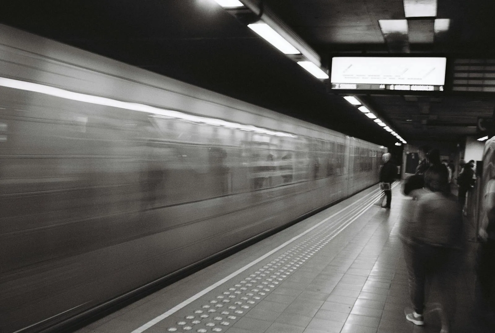 Dynamic black and white metro station scene in Brussels with commuters waiting.