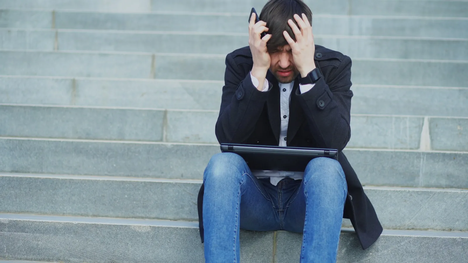 Man sitting on steps with head in hands
