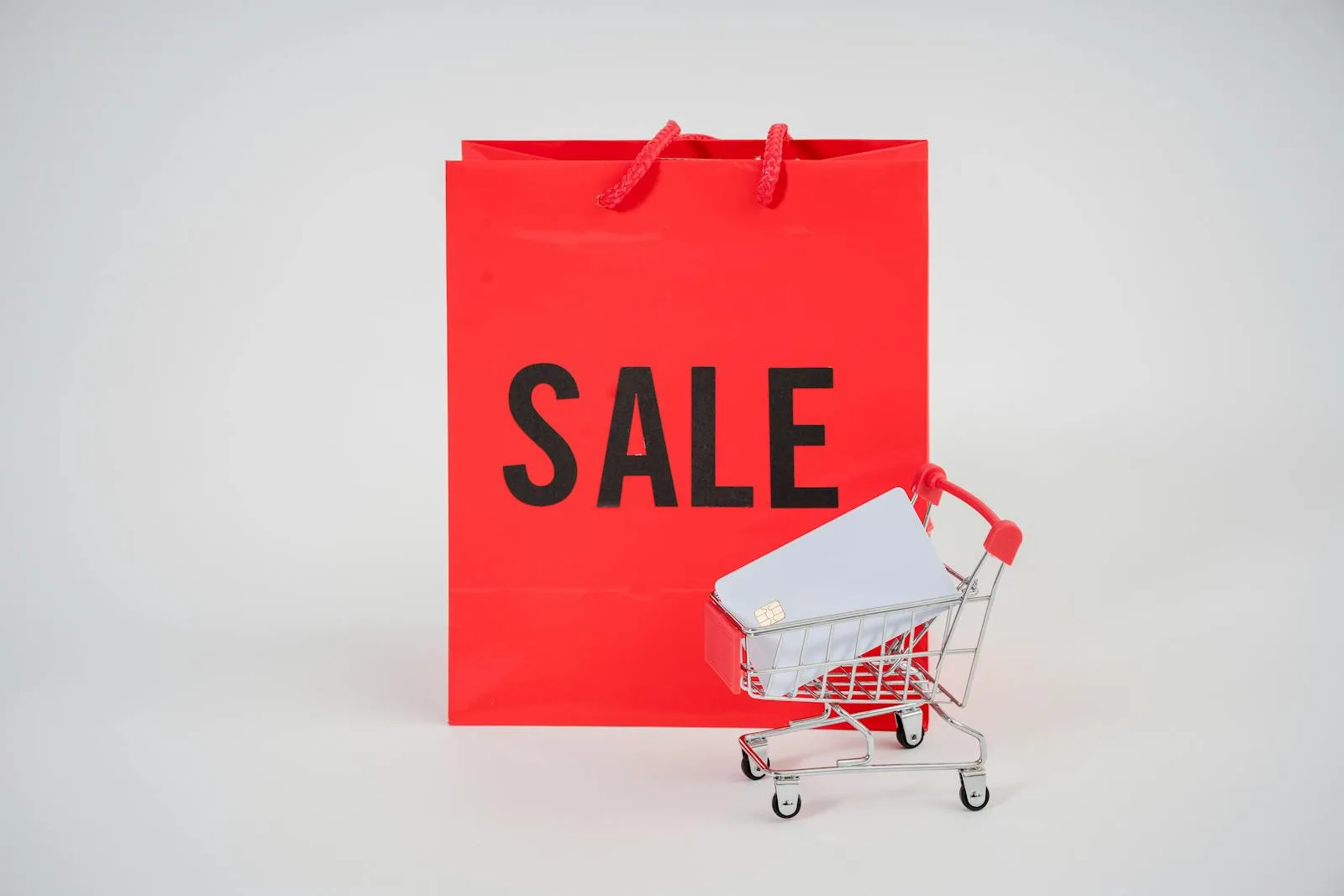 Red shopping bag with 'Sale' text and a mini cart on a white background.