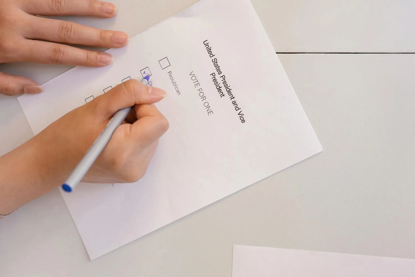 Hand placing vote on ballot form during election process, highlighting civic duty and democracy.