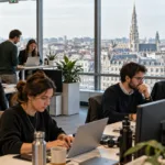 Młodzi pracownicy przy laptopach w nowoczesnym biurze w Brukseli