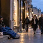 Bezdomny mężczyzna w bramie sklepu w Brukseli o zmierzchu
