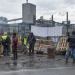 Strajkujący pracownicy przy zablokowanej bramie zakładu
