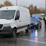 Zatrzymana furgonetka z przebitą oponą i radiowóz na parkingu przy autostradzie - wizualizacja SI