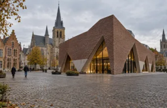 Nowoczesna hala z cegły z trójkątnymi otworami na rynku flamandzkiego miasteczka