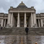 Schody i kolumny Pałacu Sprawiedliwości w Brukseli, mężczyzna z teczką od tyłu