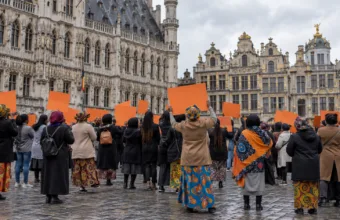 Grupa kobiet z pomarańczowymi transparentami podczas manifestacji na placu w Brukseli