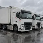 Białe ciężarówki zaparkowane na placu firmy transportowej
