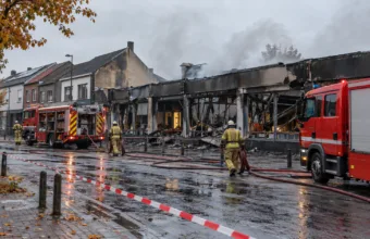Spalony budynek supermarketu i wozy strażackie na ulicy we flamandzkim mieście - wizualizacja