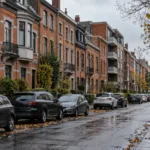 Rząd ceglanych kamienic i małych bloków mieszkalnych przy mokrej ulicy w Belgii jesienią