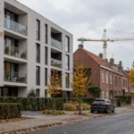 Nowy blok mieszkalny obok starszych domów szeregowych we flamandzkim miasteczku
