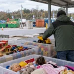 Skrzynie z używanymi zabawkami w recyparku, wolontariusz wkłada do nich zabawkową ciężarówkę