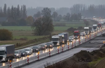 Korek samochodów i ciężarówek na autostradzie zwężonej przez roboty drogowe, pachołki i bariery wśród jesiennych pól