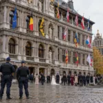 Dwoje policjantów przed renesansowym ratuszem na Grote Markt w Antwerpii, w oddali goście weselni