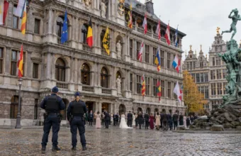 Dwoje policjantów przed renesansowym ratuszem na Grote Markt w Antwerpii, w oddali goście weselni