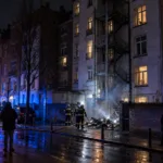 Strażacy przy ugaszonym pożarze śmieci przed budynkiem mieszkalnym w Brukseli nocą (wizualizacja SI)