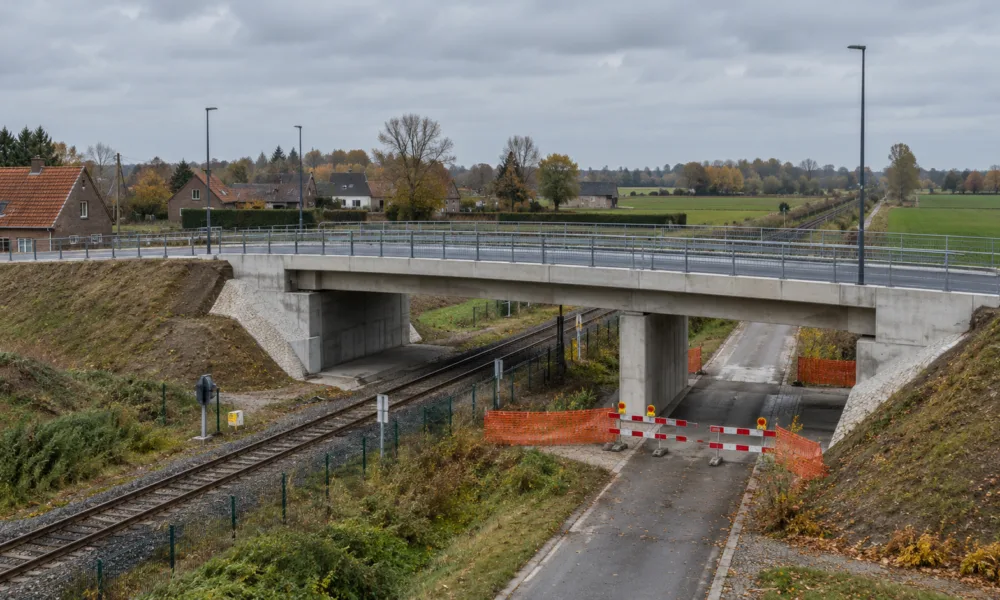 Nowy betonowy most drogowy nad linią kolejową i bariery objazdu na wiejskiej drodze we Flandrii