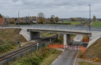 Nowy betonowy most drogowy nad linią kolejową i bariery objazdu na wiejskiej drodze we Flandrii