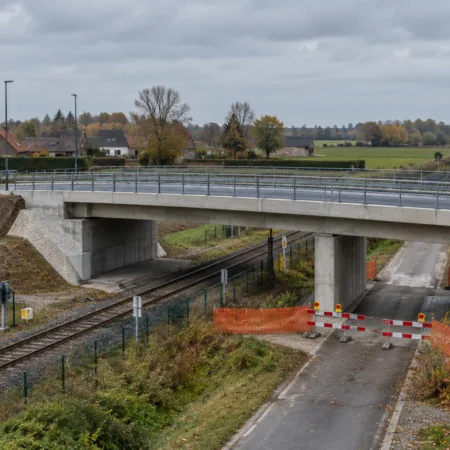 Nowy betonowy most drogowy nad linią kolejową i bariery objazdu na wiejskiej drodze we Flandrii