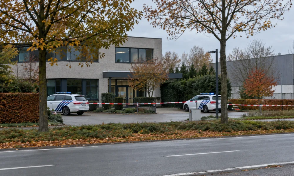 Radiowozy policji i taśma policyjna przed budynkiem biurowym w małym mieście w Limburgii