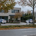 Radiowozy policji i taśma policyjna przed budynkiem biurowym w małym mieście w Limburgii