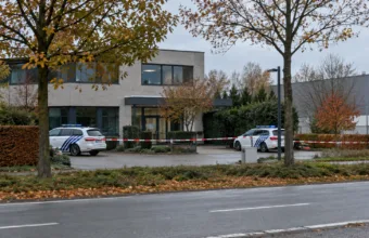 Radiowozy policji i taśma policyjna przed budynkiem biurowym w małym mieście w Limburgii
