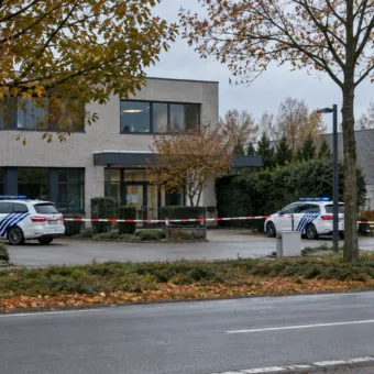 Radiowozy policji i taśma policyjna przed budynkiem biurowym w małym mieście w Limburgii