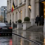 Samochody służbowe przed neoklasycznym budynkiem rządowym w Brukseli w deszczowy jesienny poranek