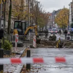 Ulica w Antwerpii odgrodzona taśmą policyjną przy wykopie, w tle radiowozy i saperzy