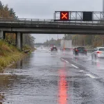 Autostrada E313 w Grobbendonk wciąż częściowo zamknięta po zalaniu – lewy pas wyłączony przy moście nad Bevrijdingsstraat, zarośnięty rów nie odprowadza wody