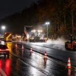 Nocne roboty drogowe na autostradzie E411 przy lesie, jeden pas ruchu otwarty